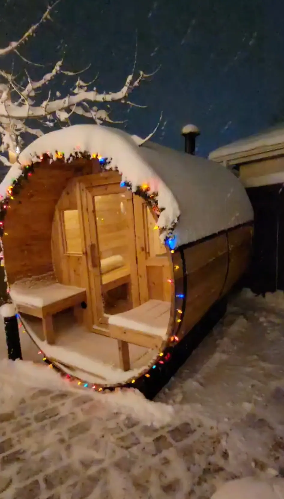 Barrel sauna in the snow with holiday lights