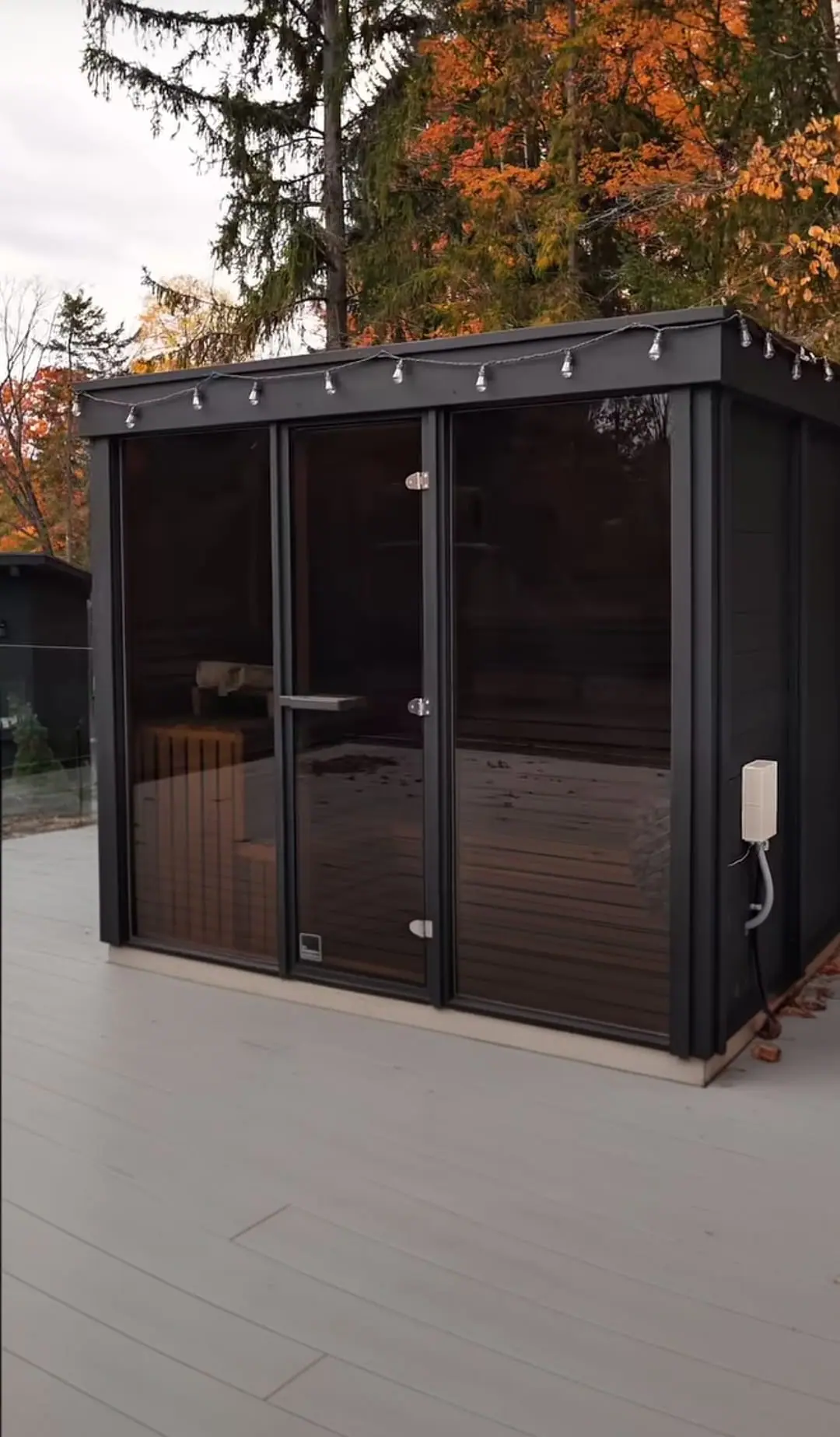 Black cube sauna on a deck in the fall
