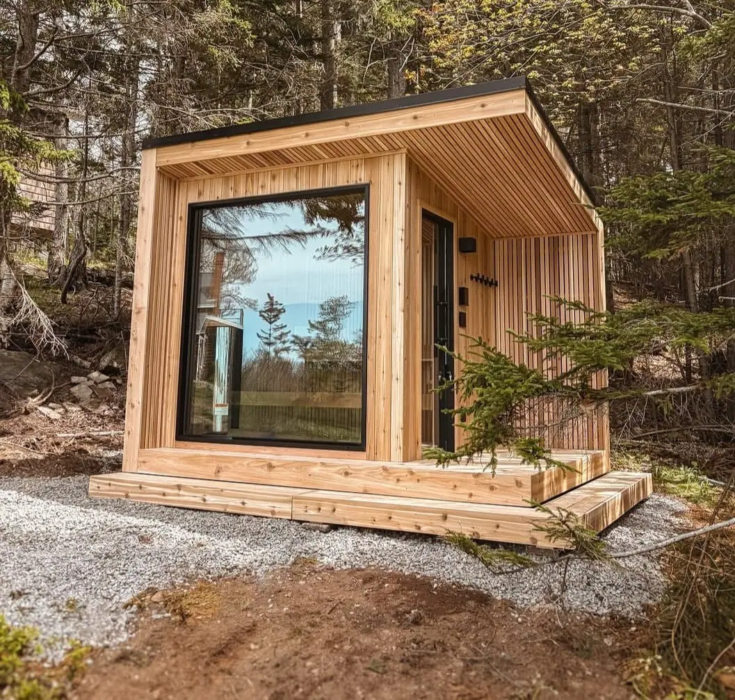 Cedar cube sauna with a large window in a forest