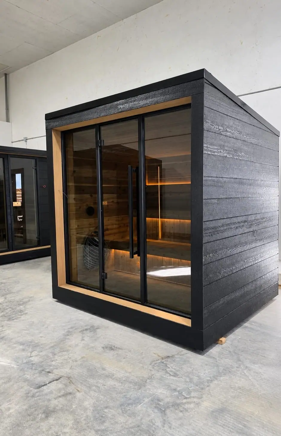 Black cube sauna with a glass front and cedar frame