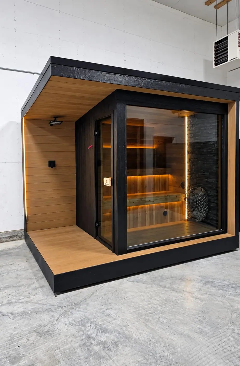 Black cube sauna with a covered porch and outdoor shower
