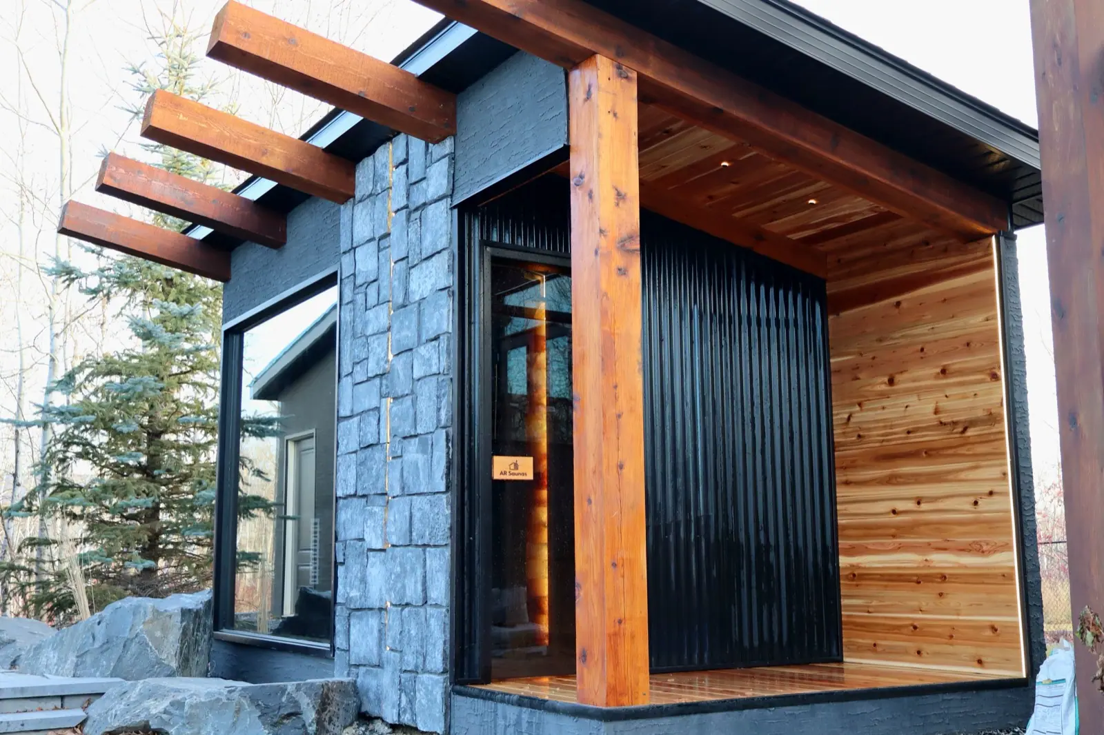 Custom sauna with a stone wall, cedar posts and a covered porch