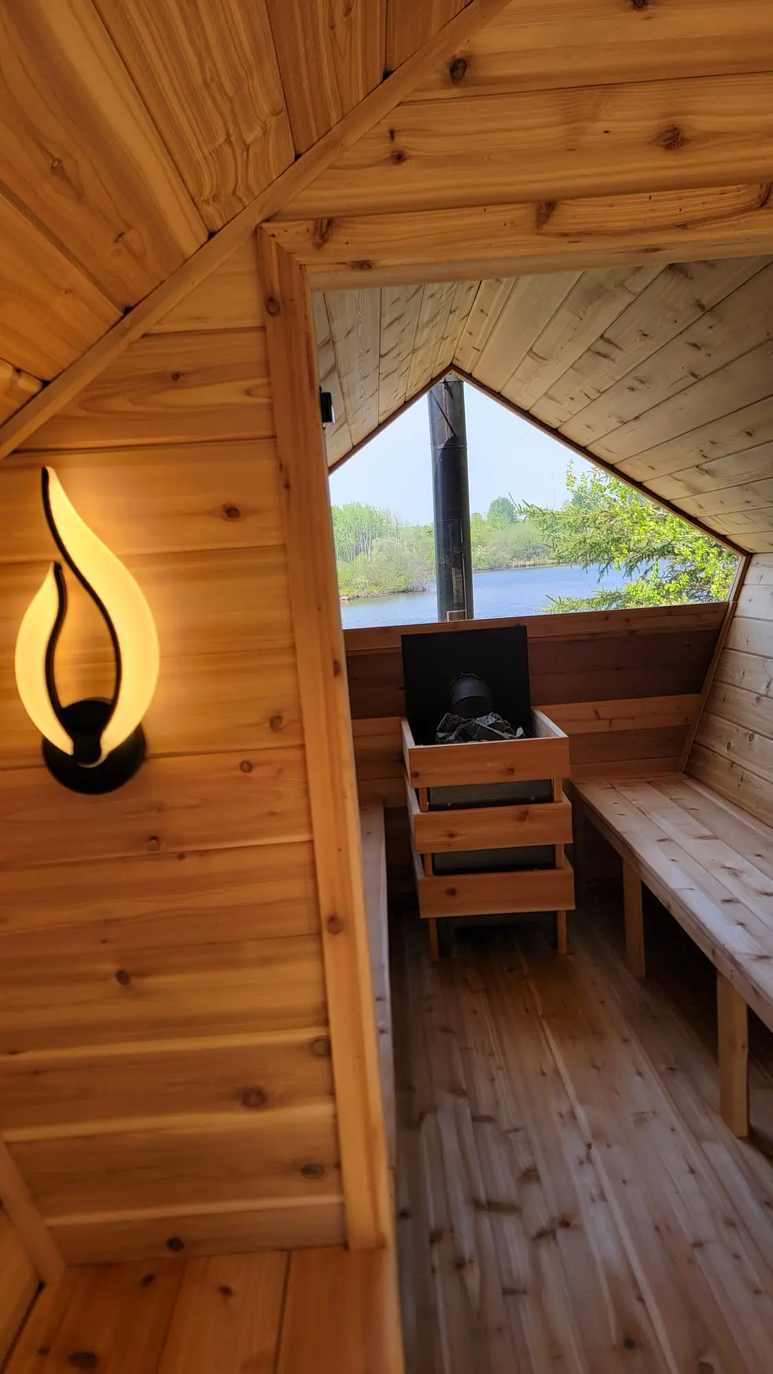 Pentagon sauna interior with flame sconce and lake view