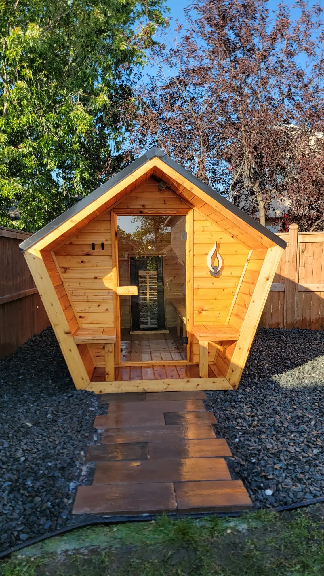 Pentagon sauna in a backyard with a stone path