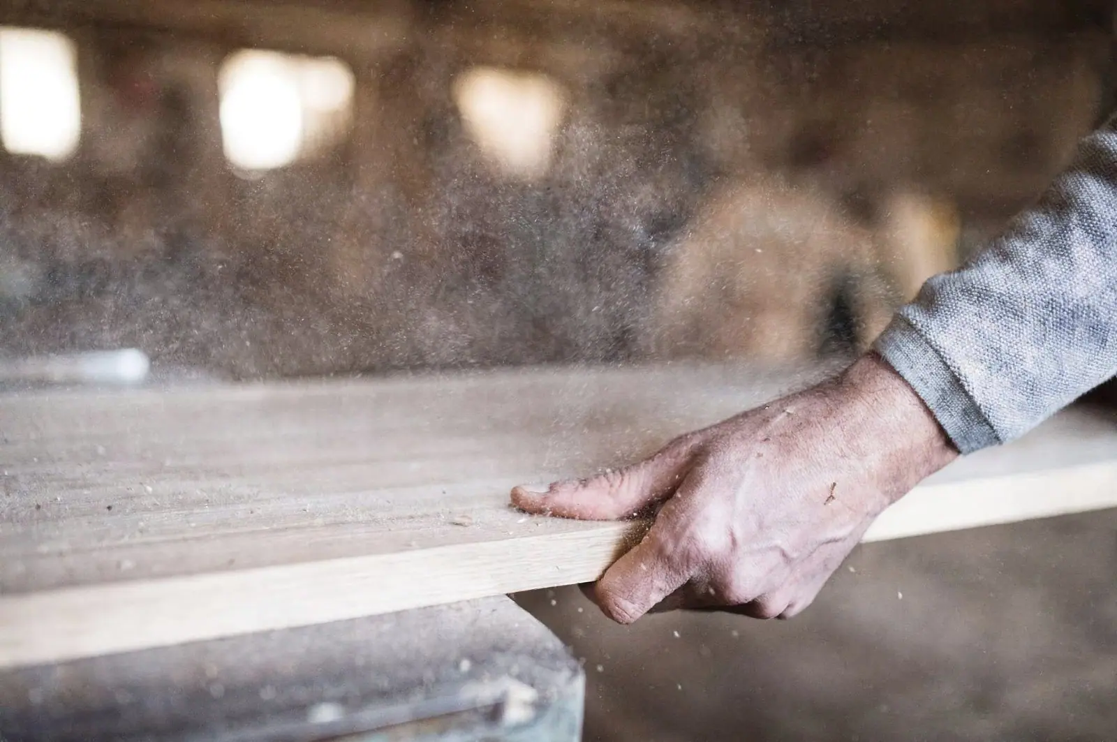 A hand guiding a cedar board through a saw in the shop
